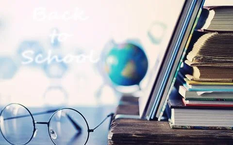 Education concept. A stack of textbooks and a book on the desk with glasses.. Stock Photos