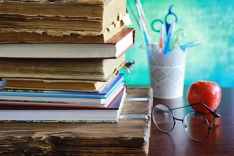 Education concept. A stack of textbooks and a book on the desk with glasses.. Stock Photos