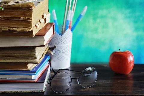 Education concept. A stack of textbooks and a book on the desk with glasses.. Stock Photos