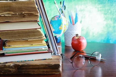Education concept. A stack of textbooks and a book on the desk with glasses.. Stock Photos