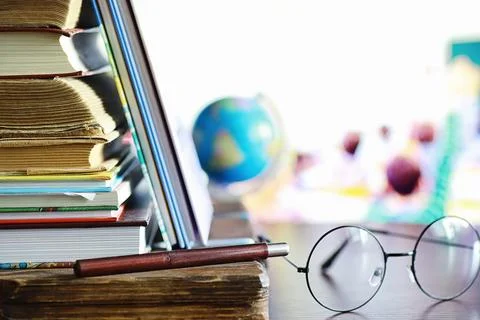 Education concept. A stack of textbooks and a book on the desk with glasses.. Stock Photos