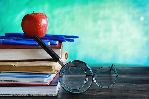 Education concept. A stack of textbooks and a book on the desk with glasses.. Stock Photos