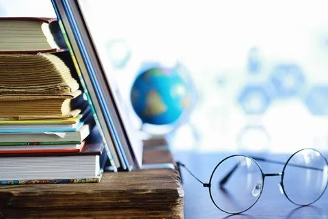 Education concept. A stack of textbooks and a book on the desk with glasses.. Stock Photos