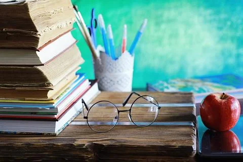 Education concept. A stack of textbooks and a book on the desk with glasses.. Stock Photos