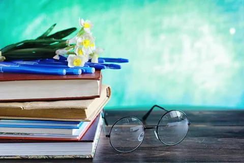 Education concept. A stack of textbooks and a book on the desk with glasses.. Stock Photos