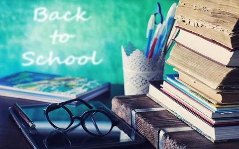 Education concept. A stack of textbooks and a book on the desk with glasses.. Stock Photos