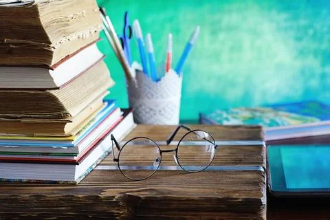 Education concept. A stack of textbooks and a book on the desk with glasses.. Stock Photos