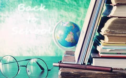 Education concept. A stack of textbooks and a book on the desk with glasses.. Stock Photos