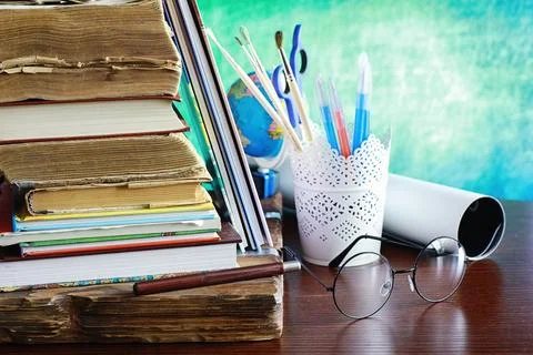 Education concept. A stack of textbooks and a book on the desk with glasses.. Stock Photos