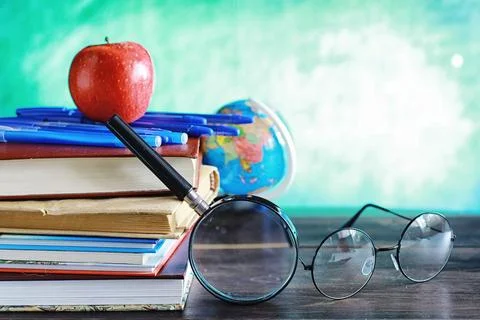Education concept. A stack of textbooks and a book on the desk with glasses.. Stock Photos