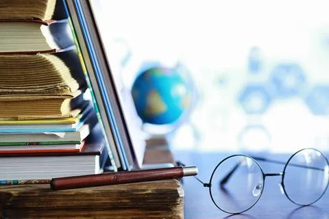 Education concept. A stack of textbooks and a book on the desk with glasses.. Stock Photos