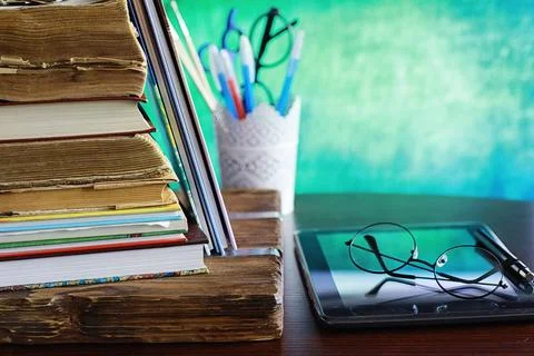 Education concept. A stack of textbooks and a book on the desk with glasses.. Stock Photos