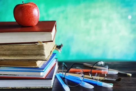 Education concept. A stack of textbooks and a book on the desk with glasses.. Stock Photos