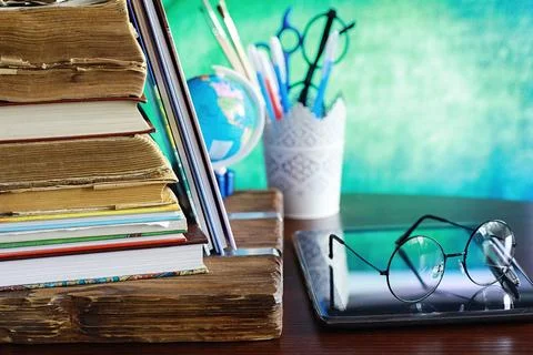 Education concept. A stack of textbooks and a book on the desk with glasses a Stock Photos
