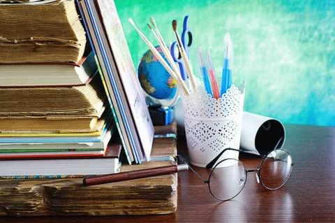 Education concept. A stack of textbooks and a book on the desk with glasses.. Stock Photos