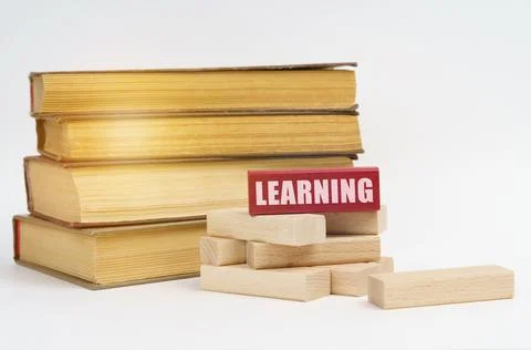 Education concept. On a white surface, a stack of books and wooden blocks, on Stock Photos