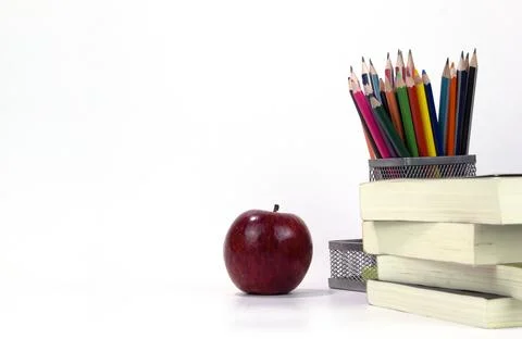 Education elements in the box with red apple and books isolated on white back Stock Photos