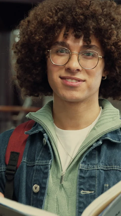 Education, face and happy man with book in library, learning and confident for Stock Footage 335804320