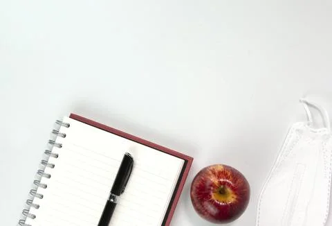 Education materials, face mask, note book, apple, pen isolated on white backg Stock Photos