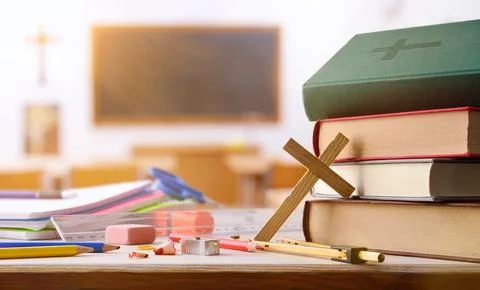 Educational supplies and religious objects on table with classroom background Stock Photos