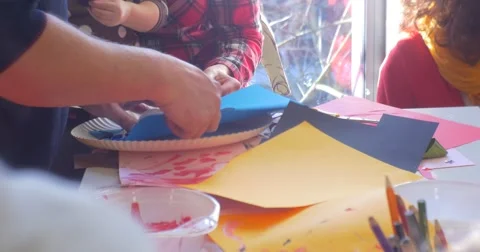 Educator's Hands Man is Cutting a Blue Paper Sheet Making Parts of Applique for Stock Footage 58478735