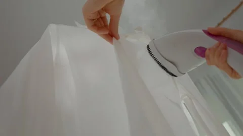 Effective clothes steaming for wrinkle-free shirts in a bright room Stock Footage 324649336