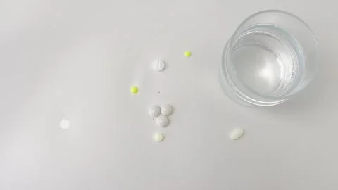 Effervescent aspirin tablet dissolving in a glass of water with various pil.. Stock Footage 335141697