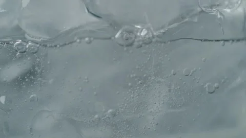 Effervescent Bubbles Rising Around Ice in Drink Stock Footage 257765693