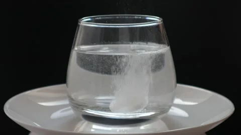 An effervescent medicine tablet dissolves in a glass of water Stock Footage 170717183
