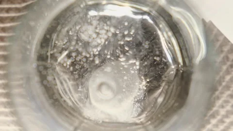 Effervescent, soluble tablet falling into glass of water, close-up Stock Footage 296018377