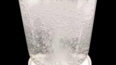 An effervescent tablet dissolves in a glass emitting a lot of bubbles. Macro vid Stock Footage 125393587