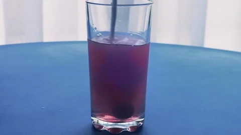 An effervescent tablet dissolves in a glass of water which turns red. Mediu.. Stock Footage 294703915