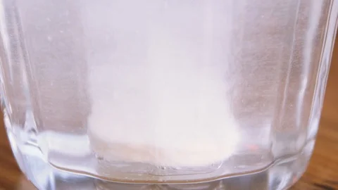 Effervescent tablet dissolves in water in a transparent glass Stock Footage 111200559