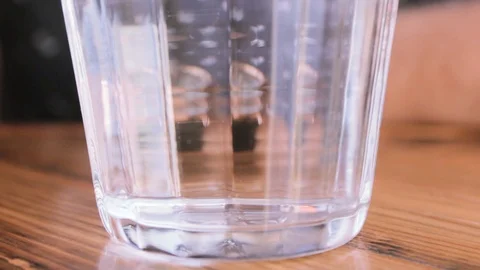 Effervescent tablet dissolves in water in a transparent glass Stock Footage 111200564