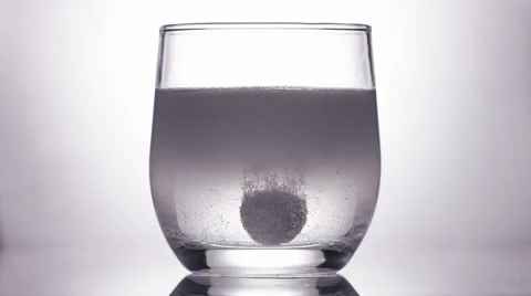 Effervescent tablet dissolving in a glass of water, in slow motion Vidéo 57485131