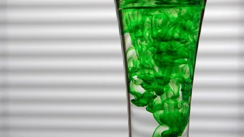 Effervescent Tablet Dissolving in Glass of Water with Green Dye Stock Footage 104618720