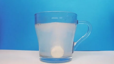 Effervescent tablet dissolving in a glass of water bubbles. Medium shot. Stock Footage 282392496