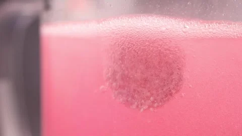 Effervescent Tablet Dissolving in Pink Liquid Stock Footage 337390784