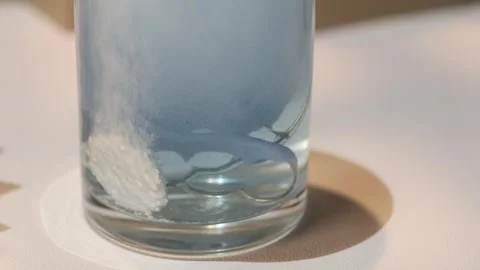 Effervescent tablet dissolving in water with a dental retainer Vídeo Stock 338960318