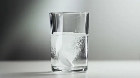Effervescent Tablet Falling into Fresh Water in Glass Cup Making Healthy Drink Stock Footage 237816966