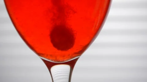 Effervescent Tablet Falling Into Glass of Red Wine and Dissolving Stock Footage 104618371