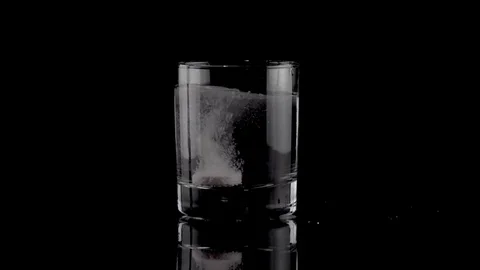 Effervescent tablet falling in a glass of water Stock Footage 81179742
