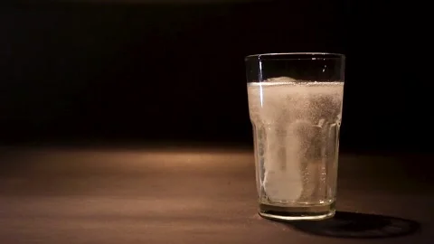 Effervescent tablet falling in a glass of water Stock Footage 244647905