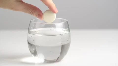 Effervescent tablet falling in glass water and dissolves with bubbles. Effe.. Stock Footage 263108758