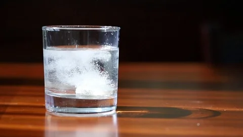 Effervescent tablet falls on a bottom of a glass of water. concept of medicine Stock Footage 106491784