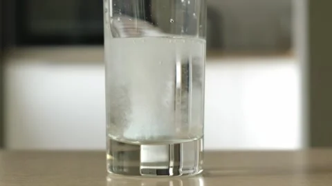 Effervescent tablet falls into a glass of water. Pill dissolving, close up Stock-Footage 320776834
