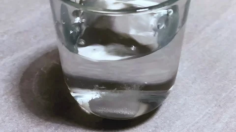 An effervescent tablet as it falls into a glass of water producing bubbles. Stock Footage 125435006
