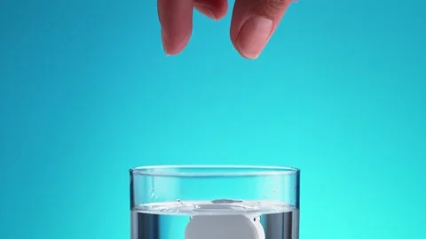 Effervescent Tablet is Released from Fingers and Falls into a Glass of Water. Stock Footage 271006505