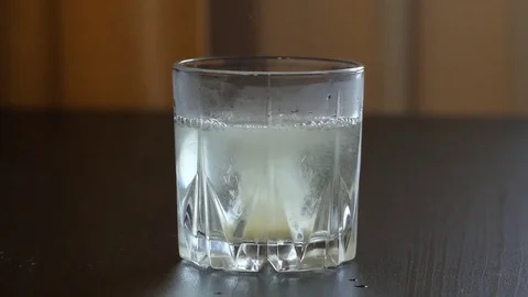 Effervescent tablets fall into a glass of water Stock Footage 83682370