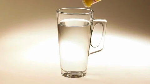 Effervescent vitamin C tablet bubbles in glass of water. Video stock 100931619